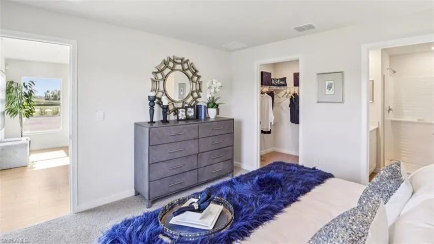 Model home. Bedroom with a walk in closet and light carpet