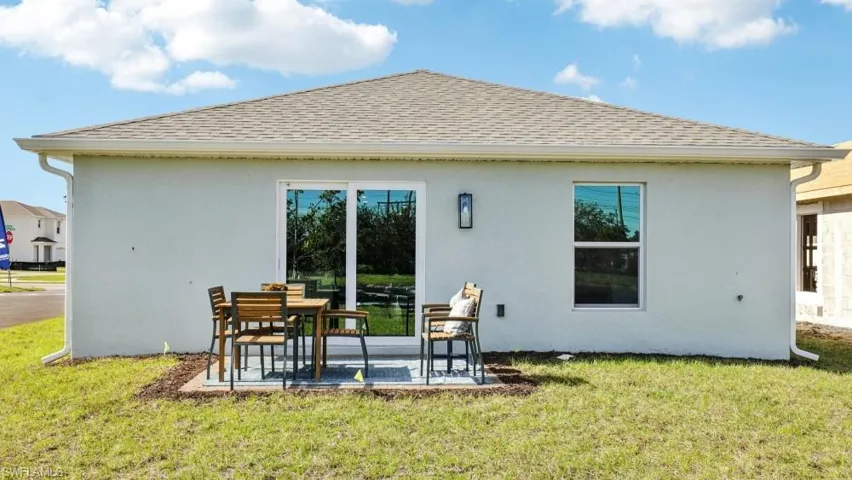 Model home. Rear view of house with stucco siding, roof with shingles, and a lawn