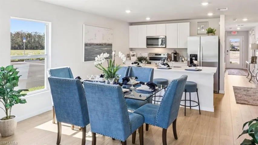 Model home. Dining room with light wood-style floors and recessed lighting