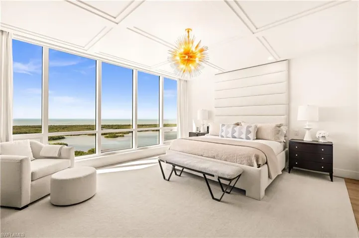 Bedroom featuring a water view, coffered ceiling, and a chandelier