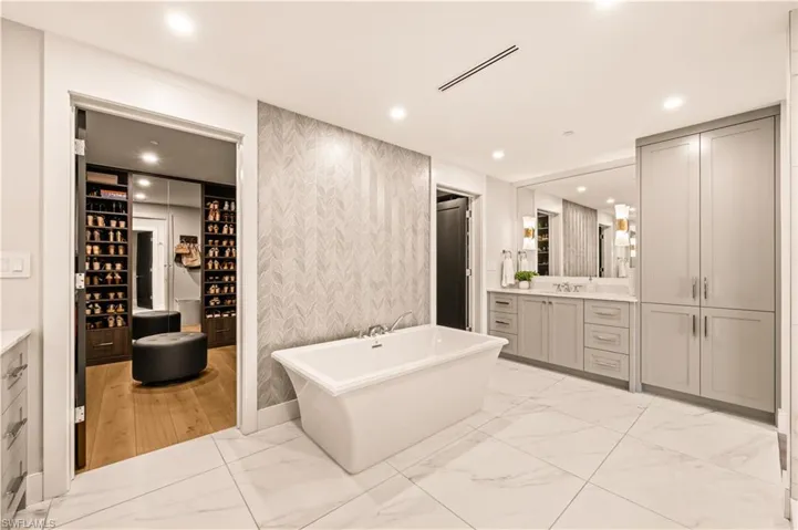 Full bath with vanity, a freestanding bath, light marble finish floors, recessed lighting, and wallpapered walls