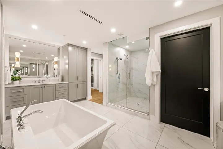 Bathroom featuring a freestanding bath, vanity, a marble finish shower, light marble finish flooring, and recessed lighting