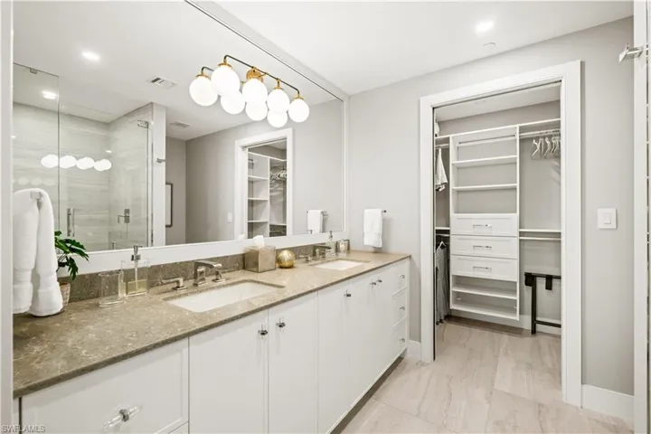 Full bath with a walk in closet, double vanity, a stall shower, and recessed lighting