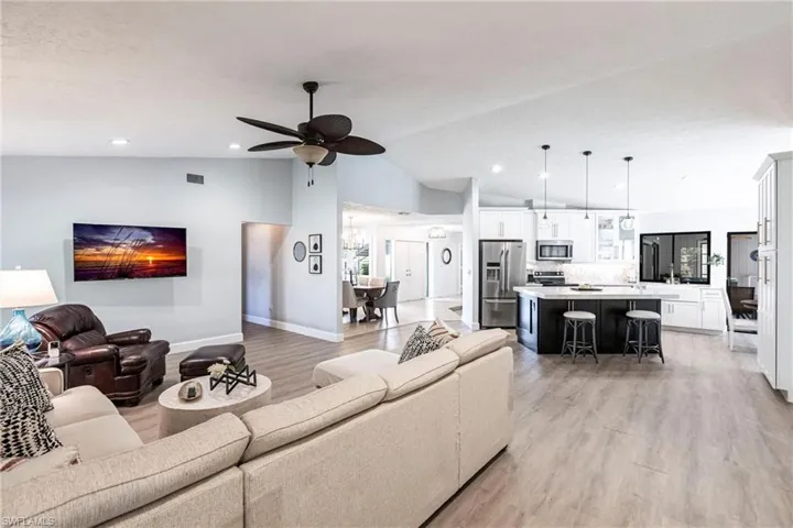 Living room with ceiling fan, visible vents, vaulted ceiling, and light wood-style floors