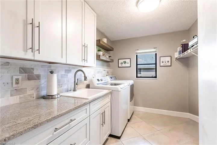 Laundry room featuring a sink, a textured ceiling, baseboards, independent washer and dryer, and cabinet space