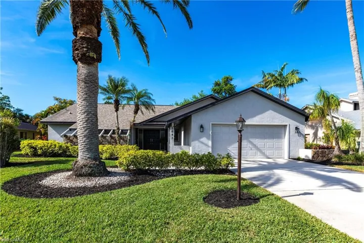 View of front of home featuring a front lawn, driveway, stucco siding, and a garage