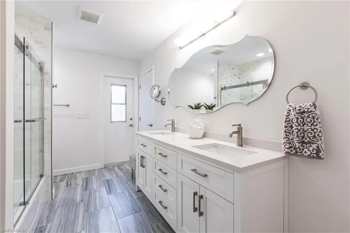 Bathroom with double vanity, visible vents, baseboards, pool bath