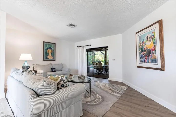 Living room with baseboards, a textured ceiling, visible vents, and wood finished floors