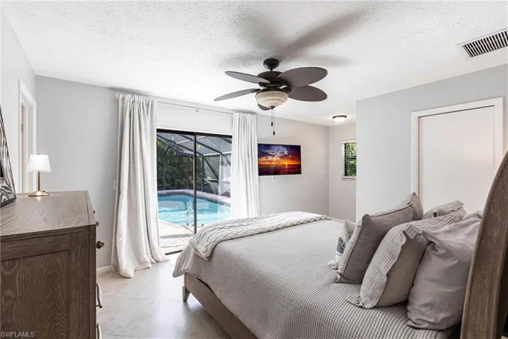 Bedroom with a textured ceiling, visible vents, baseboards, a ceiling fan, and access to exterior