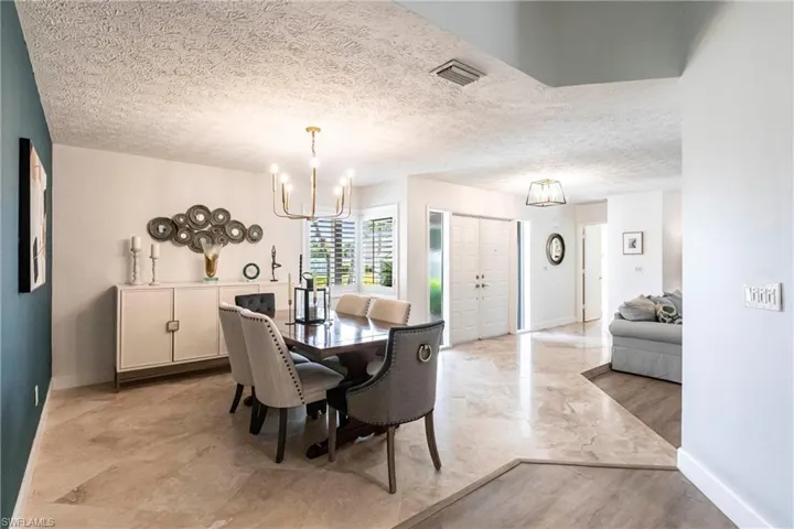 Dining space featuring a notable chandelier, a textured ceiling, baseboards, and visible vents