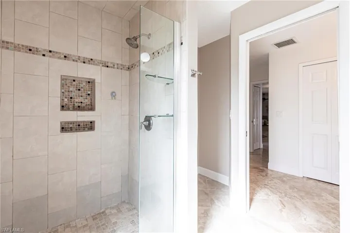 Bathroom with baseboards, visible vents, and a stall shower