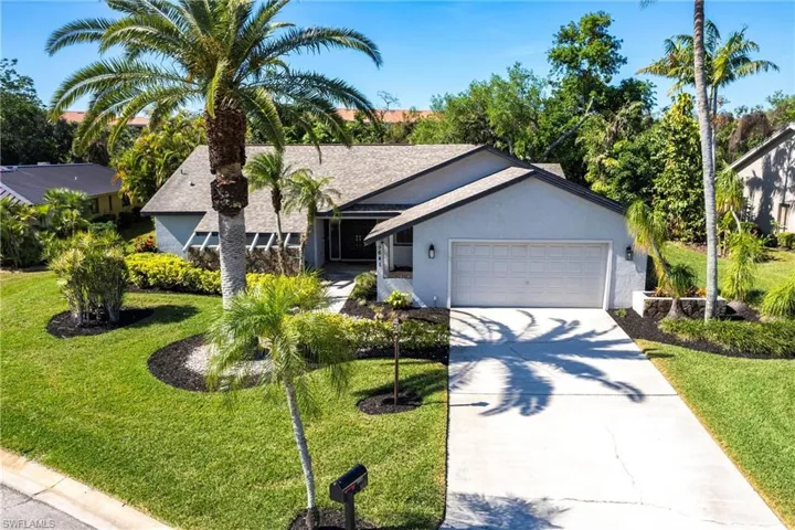 View of front of house featuring stucco siding, a front yard, driveway, and a garage