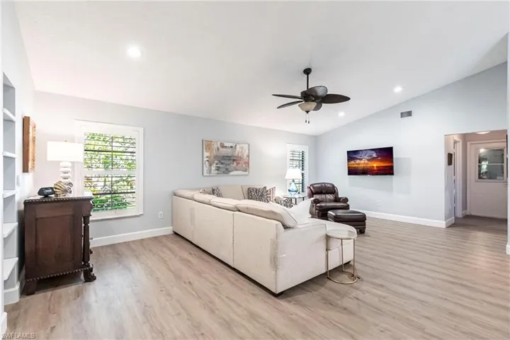 Living area featuring lofted ceiling, visible vents, ceiling fan, and light wood-type flooring