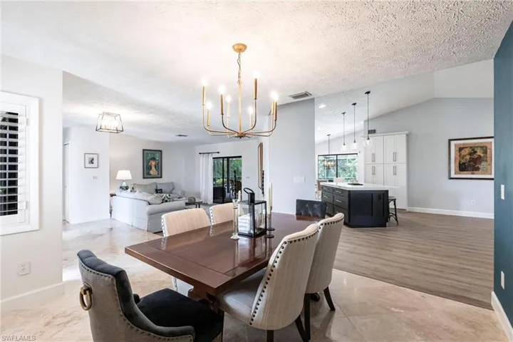 Dining space featuring lofted ceiling, baseboards, a chandelier, a textured ceiling, and visible vents