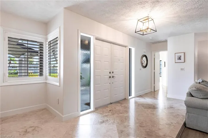 Entrance foyer featuring baseboards, an inviting chandelier, and a textured ceiling