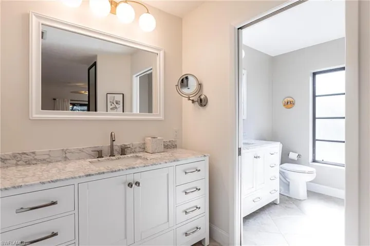 Bathroom featuring toilet, vanity, plenty of natural light, and baseboards