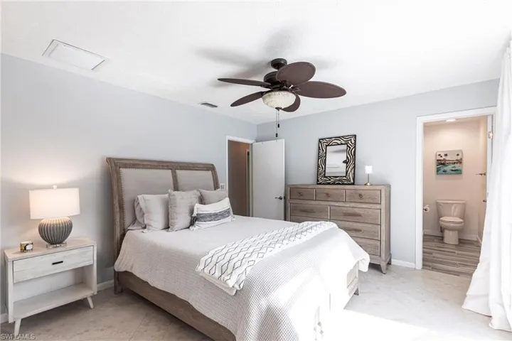 Bedroom with baseboards, ensuite bath, visible vents, and light tile patterned floors