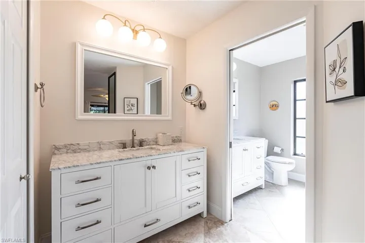 Bathroom with baseboards, toilet, and vanity
