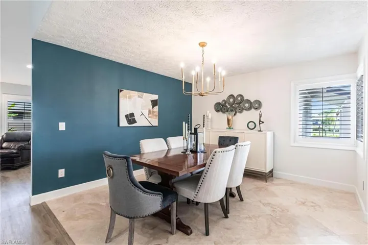 Dining area with baseboards, a textured ceiling, and a chandelier