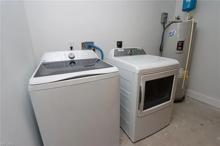 Laundry area featuring concrete floors, electric water heater, and washer and dryer