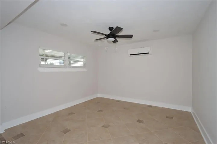 Empty room featuring a ceiling fan, light tile patterned floors, and a wall mounted mini split