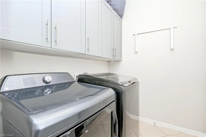 Laundry area with light tile patterned floors, separate washer and dryer, and cabinet space