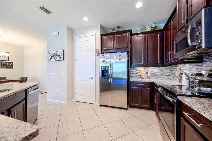 Kitchen featuring appliances with stainless steel finishes, light stone counters, decorative backsplash, and light tile patterned floors