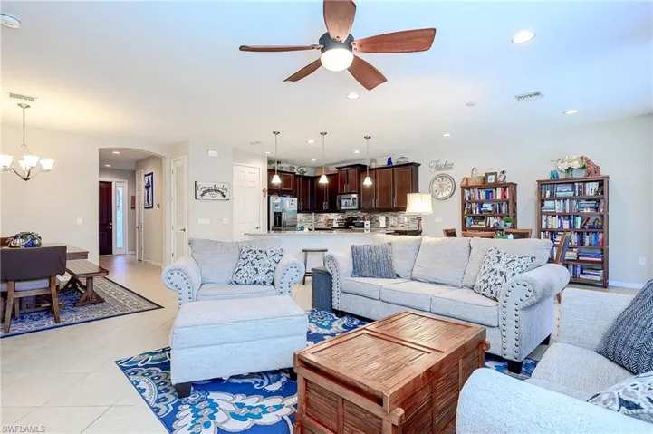 Living room with a chandelier, ceiling fan, arched walkways, light tile patterned floors, and recessed lighting