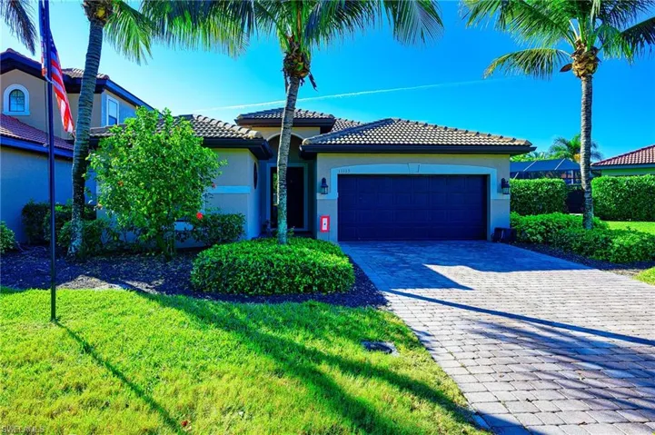 Ranch-style house featuring stucco siding, decorative driveway, a tile roof, and a front lawn