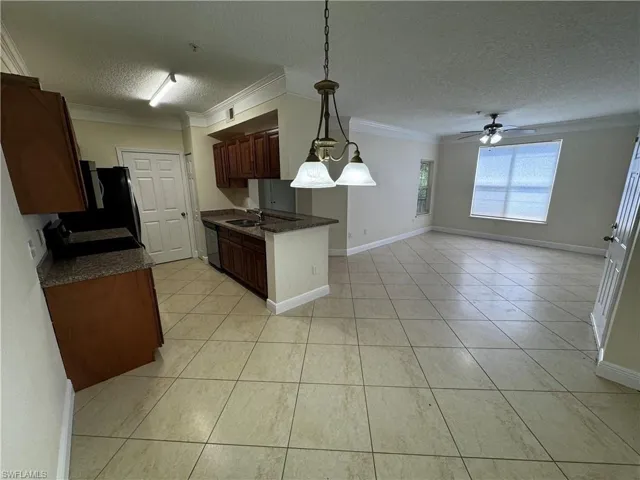 Kitchen with ornamental molding, dark countertops, a textured ceiling, and dishwashing machine