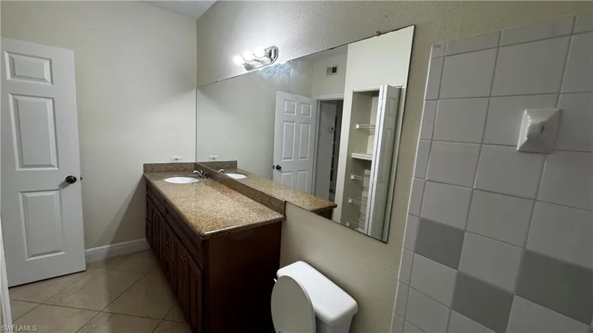 Bathroom with toilet, tile patterned flooring, visible vents, and vanity