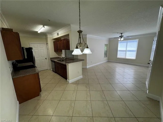 Kitchen featuring dark countertops, a sink, open floor plan, dishwashing machine, and crown molding