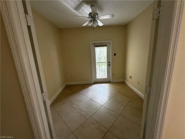 Spare room with light tile patterned flooring, ceiling fan, a textured ceiling, and baseboards