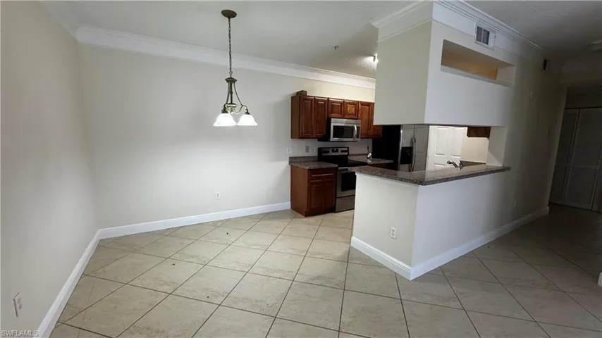 Kitchen featuring baseboards, ornamental molding, light tile patterned flooring, and appliances with stainless steel finishes