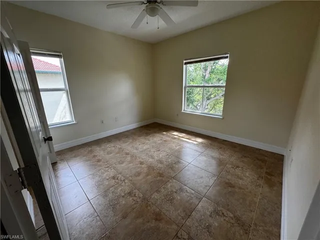 Spare room featuring ceiling fan, baseboards, and plenty of natural light