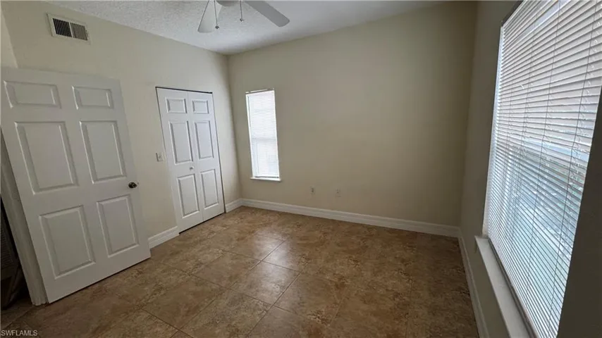 Unfurnished bedroom with a ceiling fan, visible vents, tile patterned floors, and baseboards
