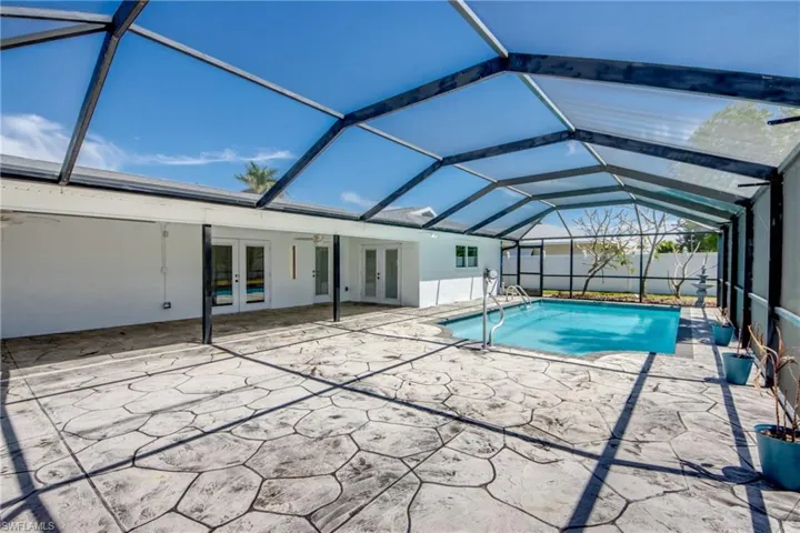 View of pool with french doors, a sunroom, a lanai, and patio surround