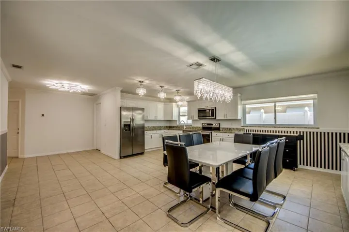 Dining space with crown molding, a chandelier, and light tile patterned floors