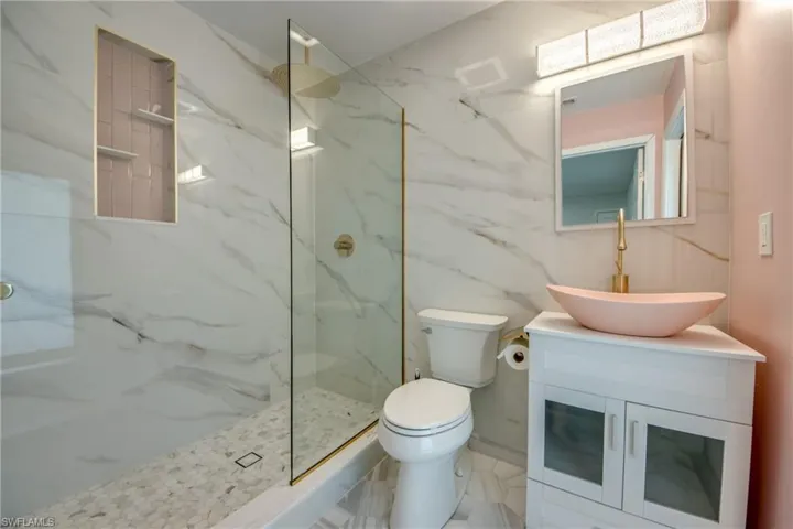 Bathroom with vanity and a marble finish shower