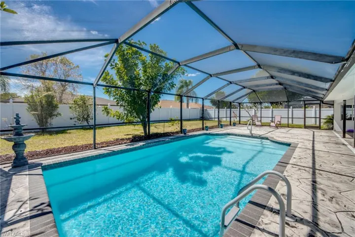 View of swimming pool featuring a sunroom, a lanai, a fenced backyard, and patio surround
