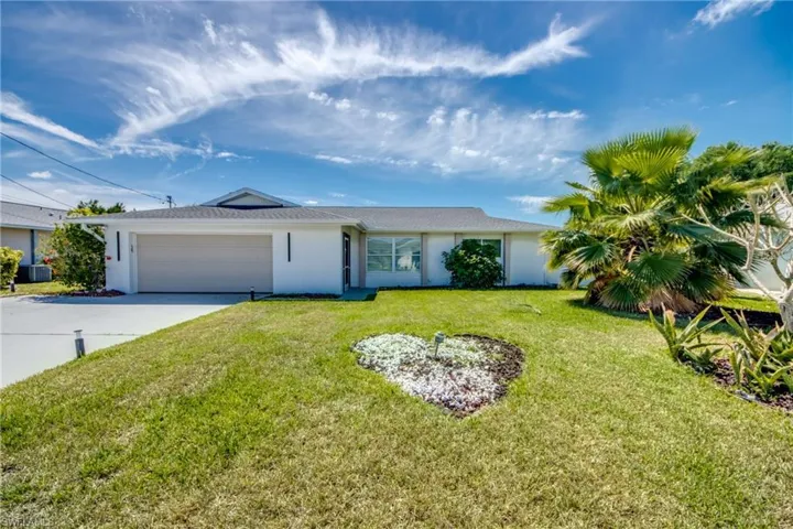 Single story home featuring a garage, concrete driveway, a front lawn, and stucco siding