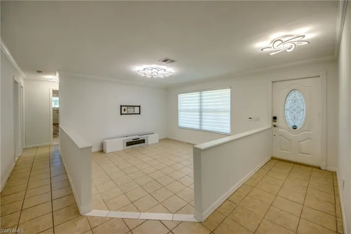 Foyer with crown molding and light tile patterned floors