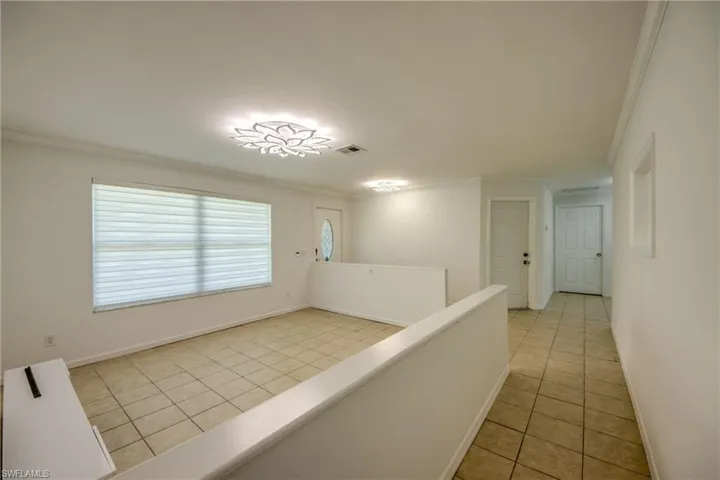Hallway featuring light tile patterned floors and crown molding