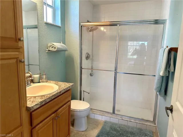 The main bathroom features a tall storage cabinet and a walk-in shower.