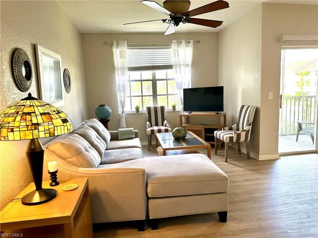 The living area has comfortable furnishings, a TV, and a ceiling fan.