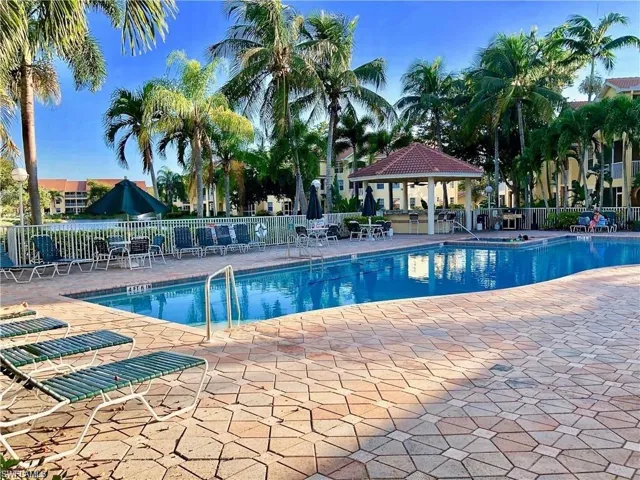 The community pool featuring a gazebo, a large patio area, and a hot tub.