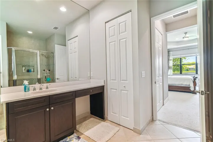 Full bath with a closet, vanity, a shower stall, light tile patterned floors, and ensuite bath