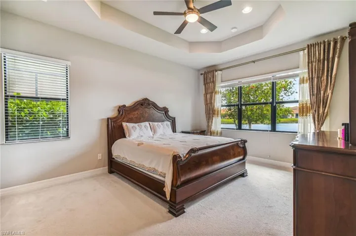 Bedroom with light carpet, a raised ceiling, a ceiling fan, and recessed lighting