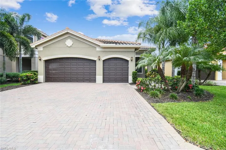 Mediterranean / spanish house featuring decorative driveway, an attached garage, stucco siding, and a tiled roof