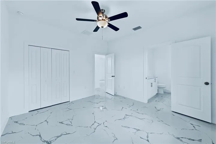 Unfurnished bedroom with connected bathroom, a closet, and ceiling fan